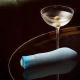 Singapore Blush Oh My Gem blue vibrator styled next to a frosted martini glass with olives—combining sophistication and sensuality for users who embrace bold, affirming solo play.