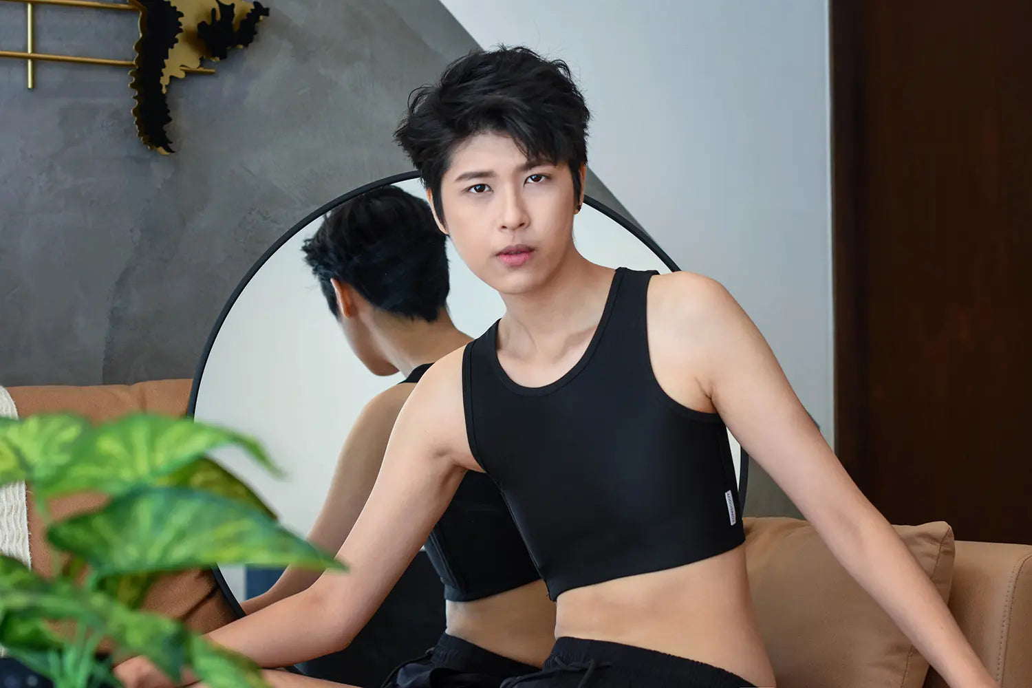 A non-binary person gazes into a mirror while wearing TOMSCOUT’s black binder, celebrating fluid identity and the freedom of self-expression with a modern, gender-inclusive wardrobe essential.