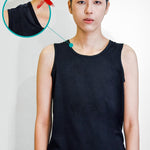 Non-binary model wearing a basic black tank top with a visible underarm seam bulge, highlighting common layering issues over traditional binders—emphasizing the need for TOMSCOUT’s ultra-smooth, low-profile chest binder solution.