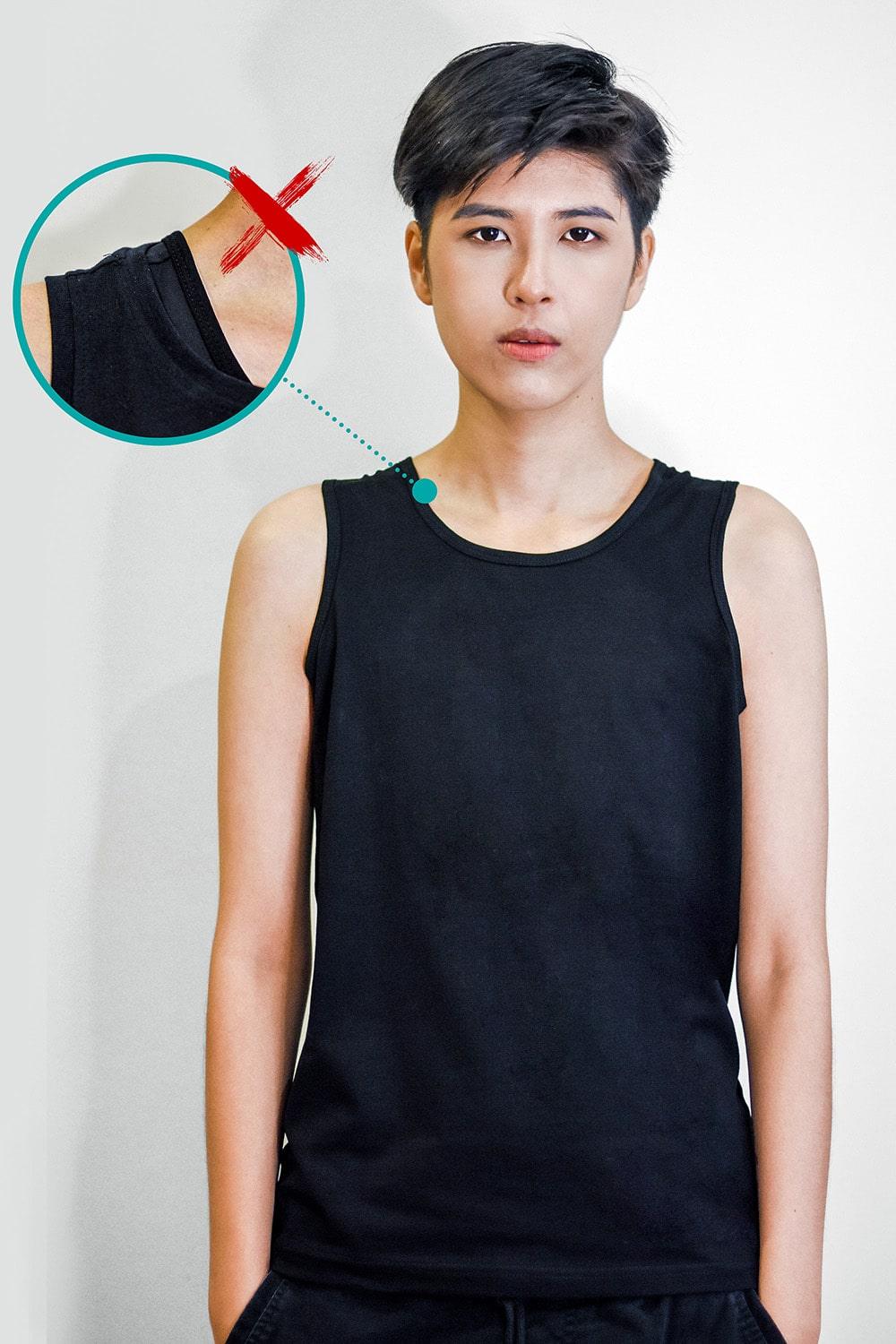 Non-binary model wearing a basic black tank top with a visible underarm seam bulge, highlighting common layering issues over traditional binders—emphasizing the need for TOMSCOUT’s ultra-smooth, low-profile chest binder solution.