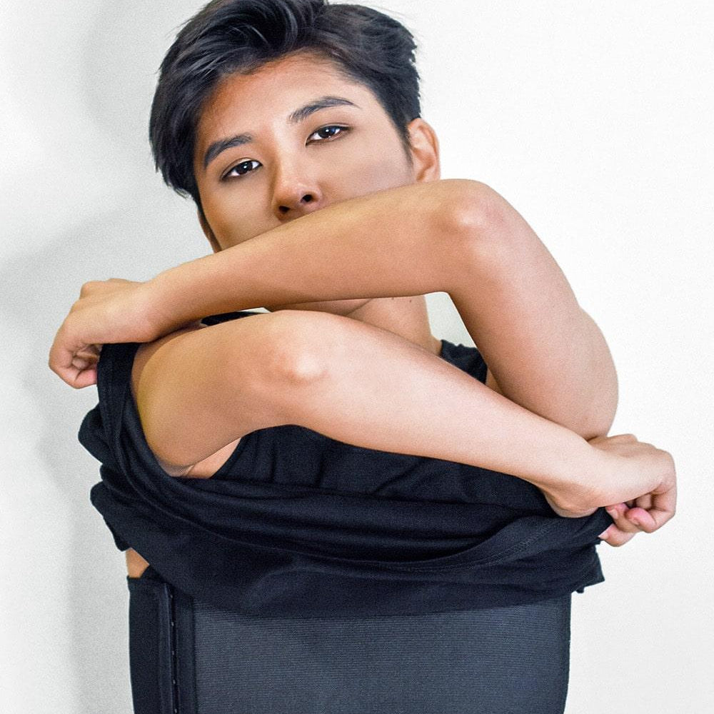 FTM individual lifting their shirt to reveal a sleek black TOMSCOUT chest binder with side hook closures and flat compression, designed for gender euphoria, breathable comfort, and discreet wear under any outfit.