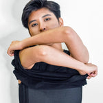 FTM individual lifting their shirt to reveal a sleek black TOMSCOUT chest binder with side hook closures and flat compression, designed for gender euphoria, breathable comfort, and discreet wear under any outfit.