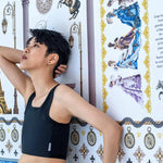 With eyes lifted toward a whimsical Parisian backdrop, a lesbian model poses in a TOMSCOUT chest binder that combines structure with softness—merging queer style with historical romance flair.