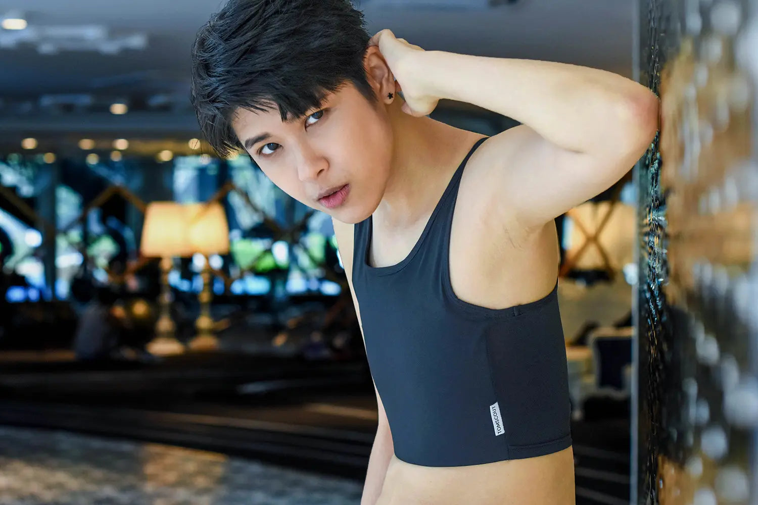 Looking directly into the lens with bold, unshakable presence, a trans man wears a TOMSCOUT binder that seamlessly contours the torso—emphasizing strength, style, and gender euphoria.