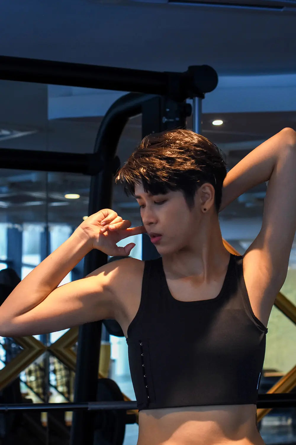 In a moment of post-workout serenity, a non-binary person stretches in a TOMSCOUT compression top, showcasing toned arms and breathable, moisture-wicking fabric ideal for active lifestyles.