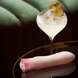Singapore Blush Oh My Gem rechargeable vibrator placed beside a crystal coupe cocktail with ice and dried pineapple, styled on a luxe velvet surface—fusing elegance and femme-forward pleasure for lesbian and non-binary users.