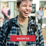 Youthful queer person in plaid flannel and cropped hair laughing joyfully, captioned “For Your Daughter”—a perfect visual for gifting a TOMSCOUT card to support their journey, style, or comfort needs.
