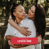 Smiling queer couple embracing affectionately in the park, representing the joy of gifting a TOMSCOUT digital gift card to your partner—affirming love and pride through thoughtful, inclusive giving.