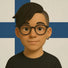 Stylish non-binary individual with an undercut and swept-over black hair wears round glasses and a hoop earring, posing against the Finnish flag to represent queer identity across global cultures.