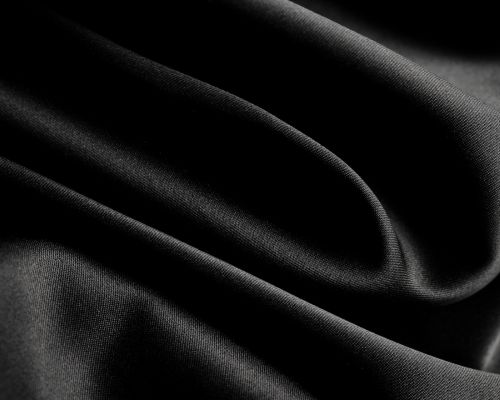 Close-up of sleek, satin-finish black fabric used in TOMSCOUT’s luxe gender-affirming apparel line—smooth, lightweight, and ultra-soft against the skin. Ideal for androgynous wearers prioritizing comfort and elegance in dysphoria-safe design. Wash on delicate, hang to preserve silk-like sheen. TOMSCOUT SAPPHIRE Chest Binder