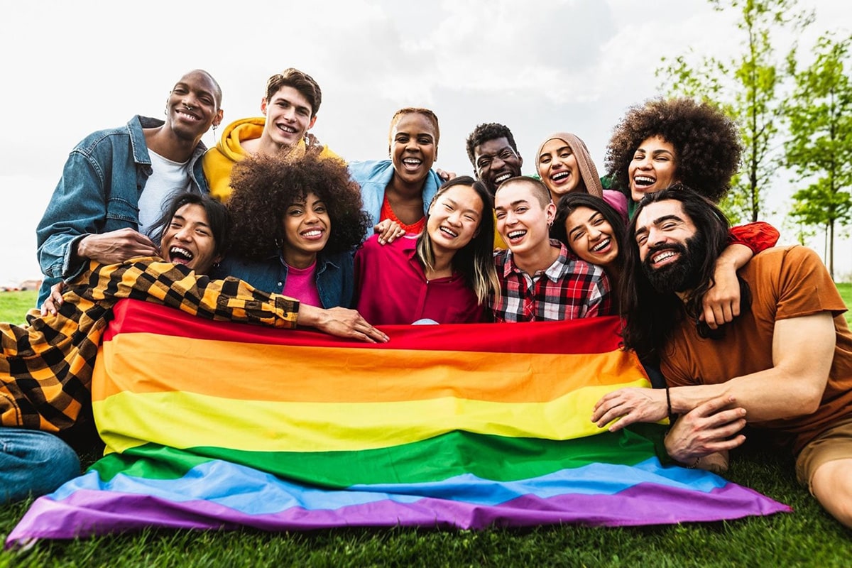 Gathering of diverse non-binary, androgynous tomboys, transmen, and lesbians, all expressing joy and unity in pride, featured on the TOMSCOUT Chest Binders, LGBTQ+ Clothing, Tote Bags LGBTQ owned E-commerce Store Home Page.