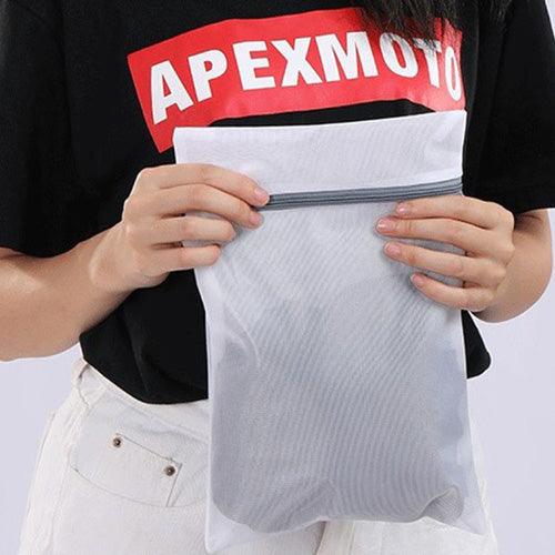 Person holding a mesh laundry bag filled with folded garments—perfect for safe washing of TOMSCOUT’s binders and boxer briefs. Zipper closure keeps your gender-affirming essentials secure and intact.