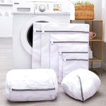 Full TOMSCOUT laundry bag set displayed in various sizes beside a modern washing machine. Designed for all clothing types—especially binders and compression wear—for optimal washing protection and long-term durability.