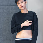 Androgynous model wearing black TOMSCOUT boxer briefs with a sleek navy and white waistband, paired with a cropped black top. The ultra-soft stretch cotton hugs the hips without riding up—perfect for non-binary folks seeking body-affirming essentials with minimal seams and maximum confidence.