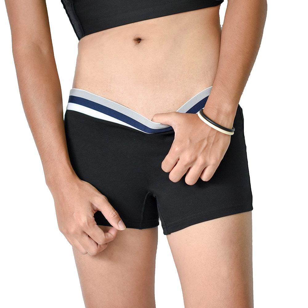 Close-up of a tomboy-presenting person adjusting the waistband of TOMSCOUT’s black boxer briefs. The snug athletic band offers stylish support without digging, designed for queer bodies craving gender euphoria and everyday ease.