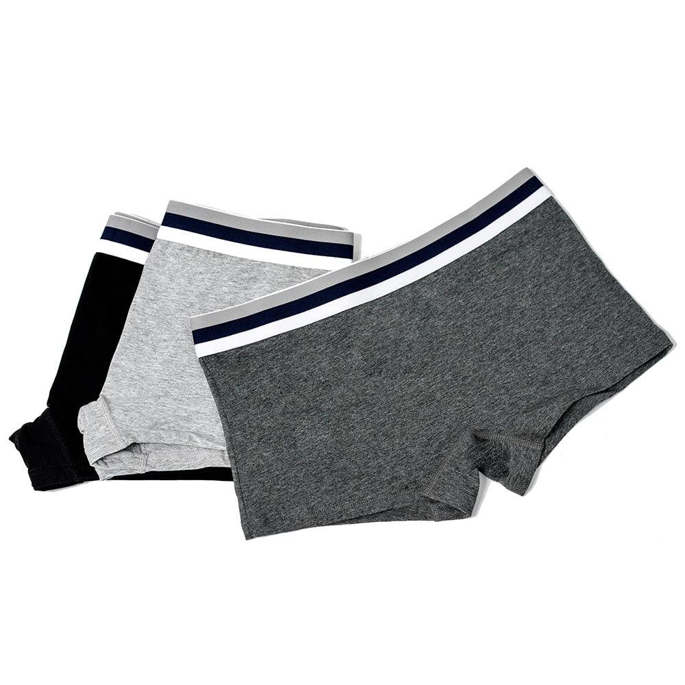 Flat lay of TOMSCOUT’s classic boxer briefs in black, light grey, and charcoal, stacked to show off their signature striped waistband. Made for gender-diverse wearers who want soft, functional underwear that feels right—whether lounging, layering, or on the move.