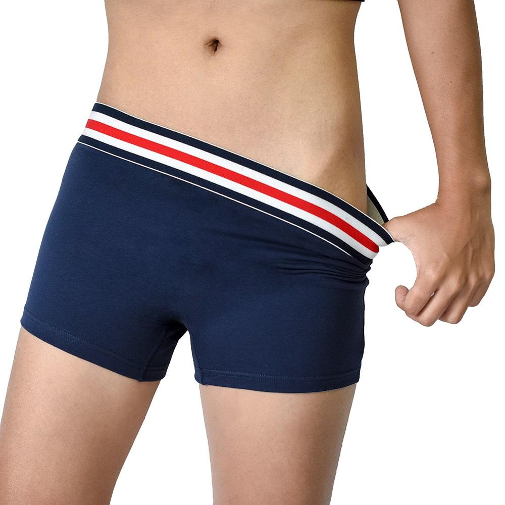 Close-up of a non-binary person adjusting navy TOMSCOUT boxer briefs, showcasing the elastic waistband and body-hugging fit. Designed for all-day movement, comfort, and a gender-affirming alternative to traditional underwear.