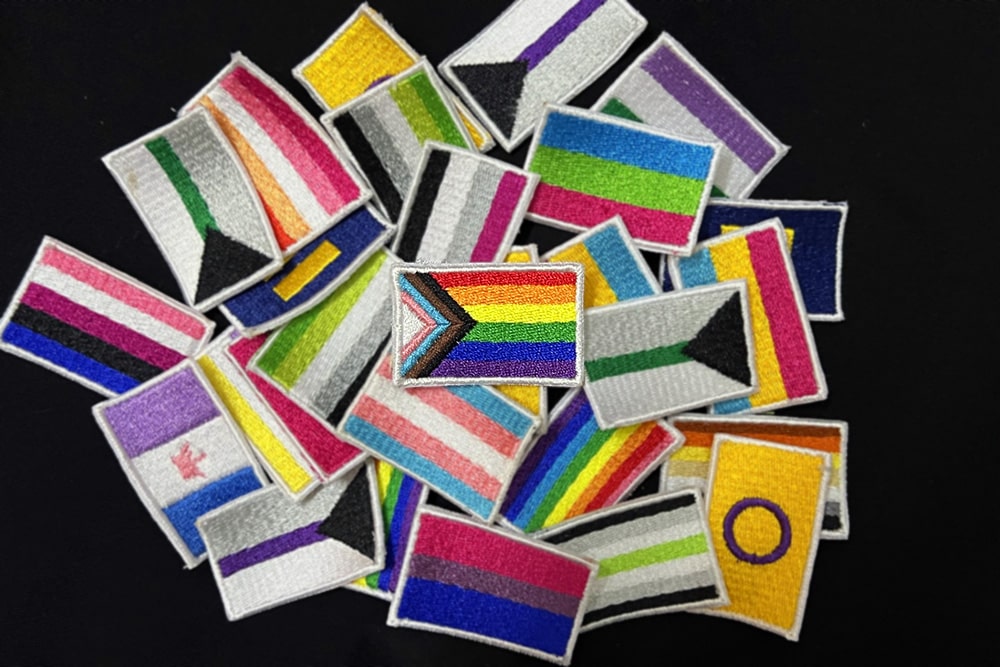 Embroidery piece featuring a collection of pride flags, each symbolizing different LGBTQ+ communities and identities.