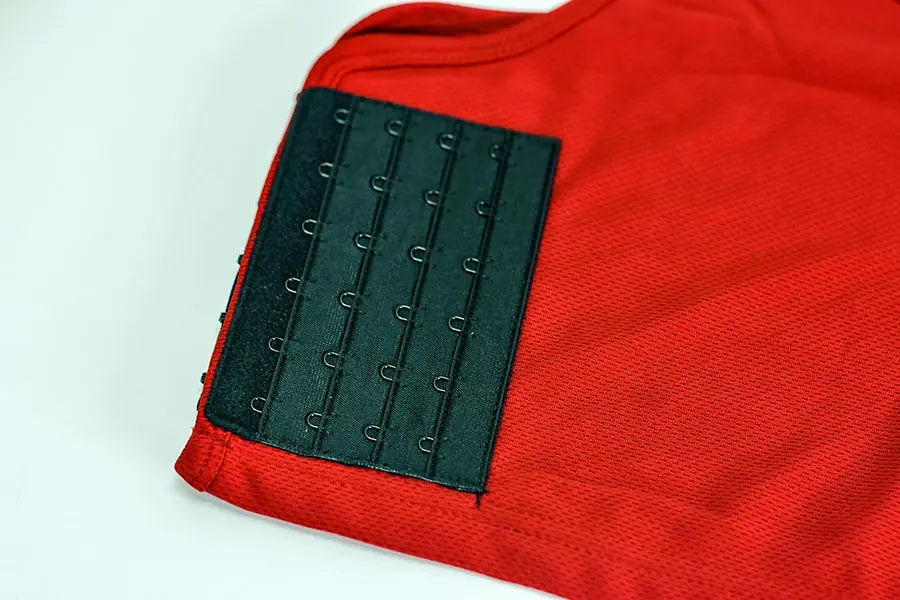 Close-up of a red TOMSCOUT chest binder featuring a triple-row hook-and-eye closure panel, designed for customizable compression and all-day comfort. The breathable mesh fabric enhances airflow, making it ideal for active FTM individuals seeking discreet, adjustable chest flattening. Part of the Free Chest Binder Program supporting gender-affirming access.