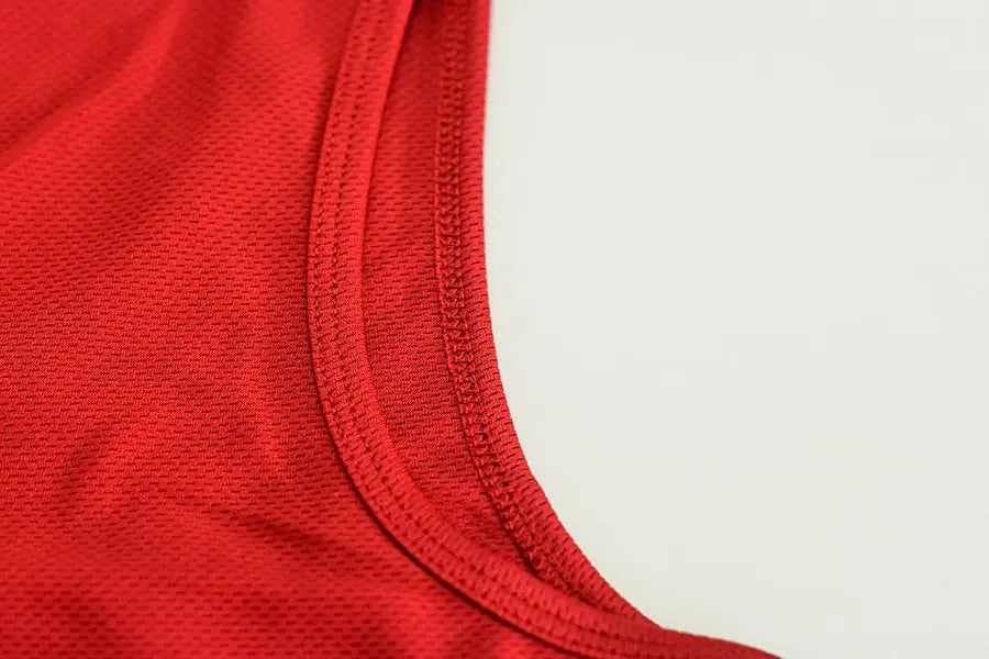Detail shot of the armhole seam on a red TOMSCOUT chest binder, showcasing reinforced stitching and breathable athletic mesh. Designed for non-binary individuals seeking a secure, chafe-free fit during daily wear or workouts, this gender-affirming binder balances compression and comfort. Eligible through TOMSCOUT’s Free Chest Binder Program.