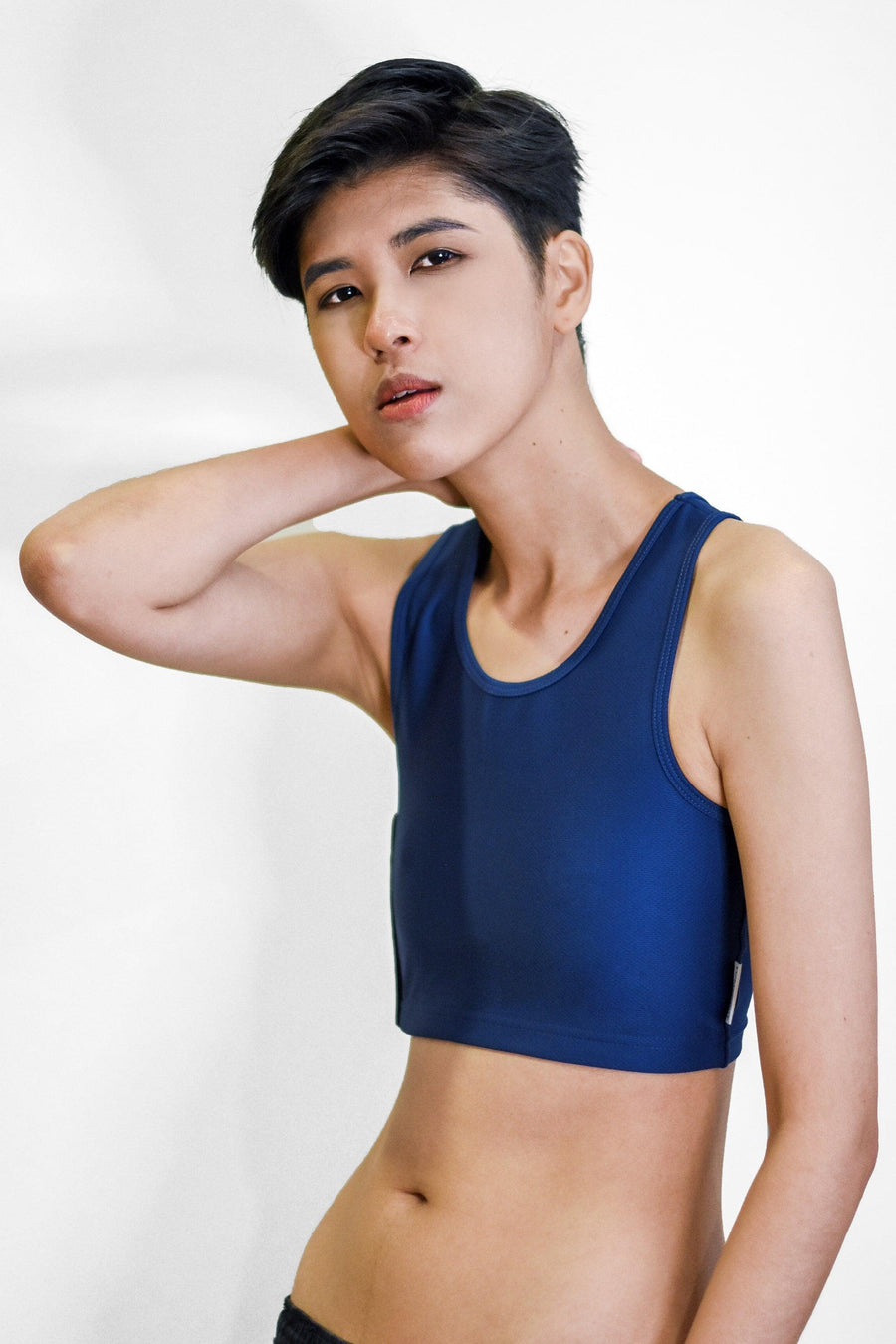 A non-binary Tomboy wearing a navy color of a non-bandage TOMSCOUT Chest Binder to fight body dysphoria, TOMSCOUT ACTIVE BINDER.