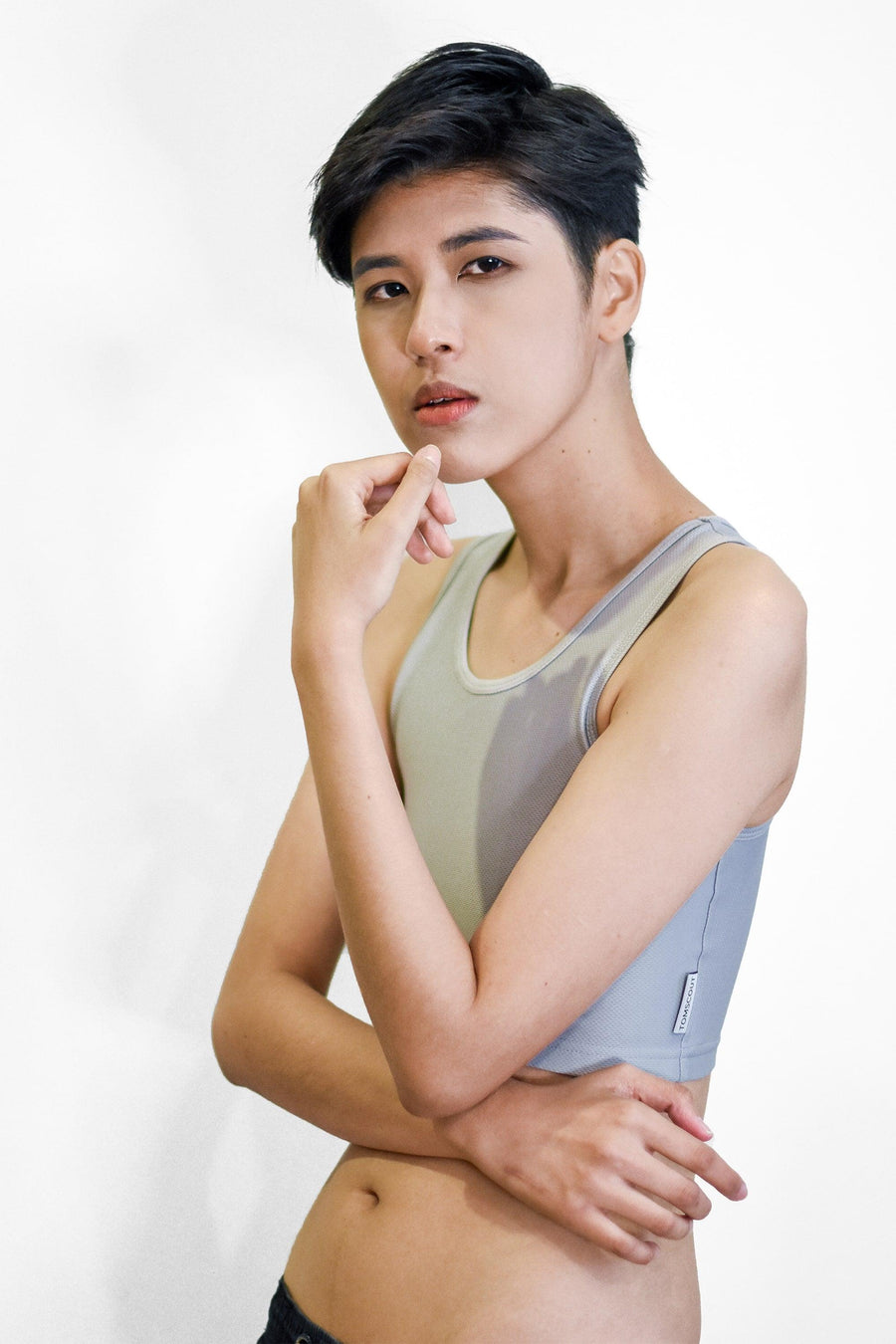 A non-binary Tomboy wearing a grey color of a non-bandage TOMSCOUT Chest Binder to fight body dysphoria, TOMSCOUT ACTIVE BINDER.