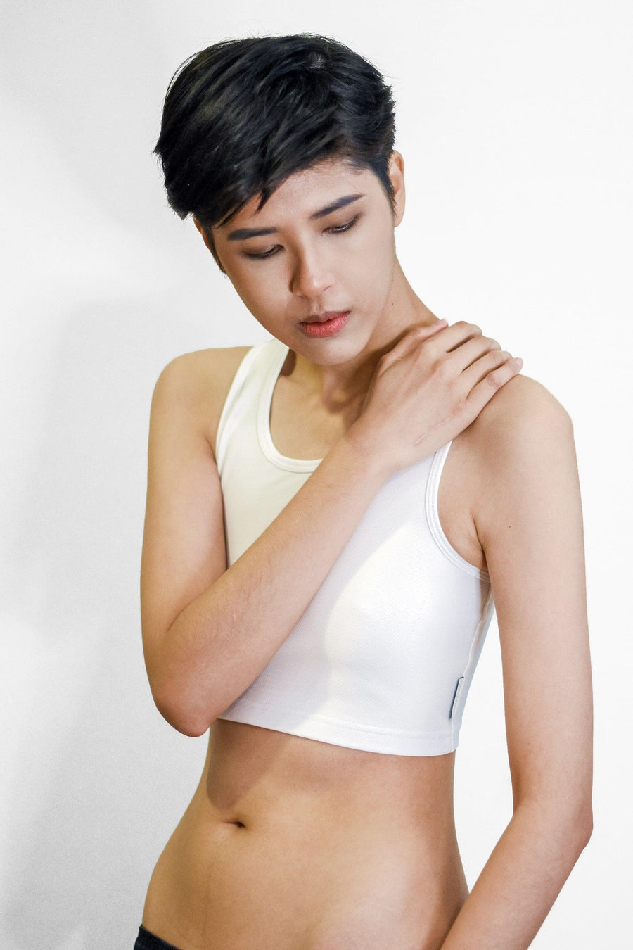 A non-binary Tomboy wearing a white color of a non-bandage TOMSCOUT Chest Binder to fight body dysphoria, TOMSCOUT ACTIVE BINDER.