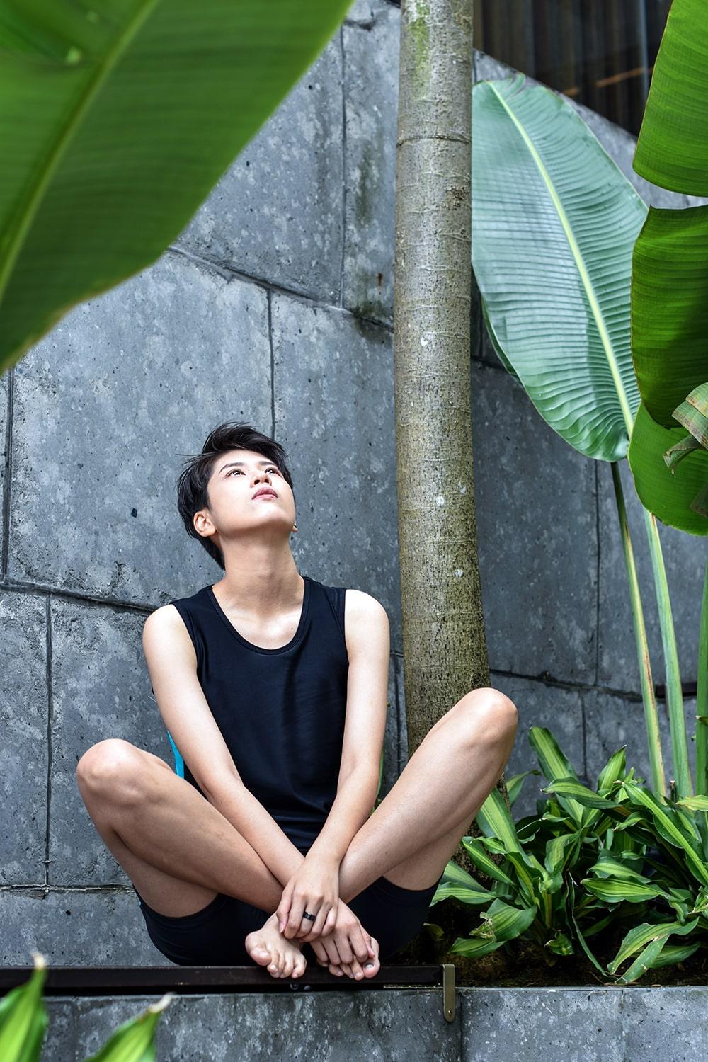 A non-binary androgynous tomboy, transgender man wearing a black color of a bandage TOMSCOUT Swimming Chest Binder to fight body dysphoria and swimming in the pool, TOMSCOUT SAPPHIRE SWIMMING BINDER.