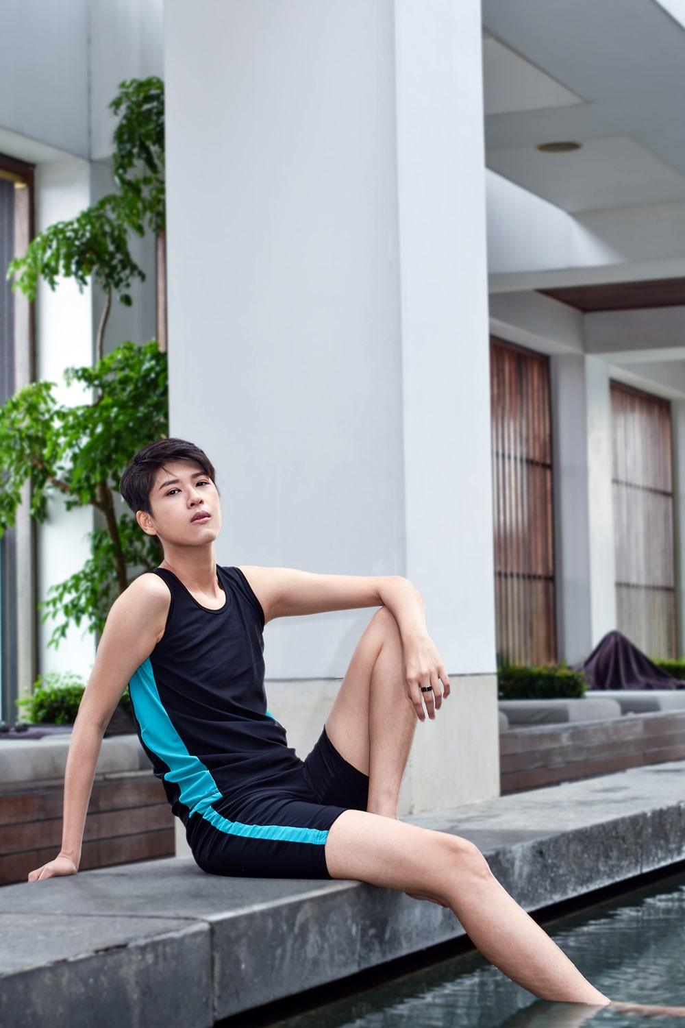 A non-binary androgynous tomboy, transgender man wearing a black color of a bandage TOMSCOUT Swimming Chest Binder to fight body dysphoria and swimming in the pool, TOMSCOUT SAPPHIRE SWIMMING BINDER.