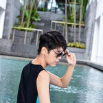 A non-binary androgynous tomboy, transgender man wearing a black color of a bandage TOMSCOUT Swimming Chest Binder to fight body dysphoria and swimming in the pool, TOMSCOUT SAPPHIRE SWIMMING BINDER.