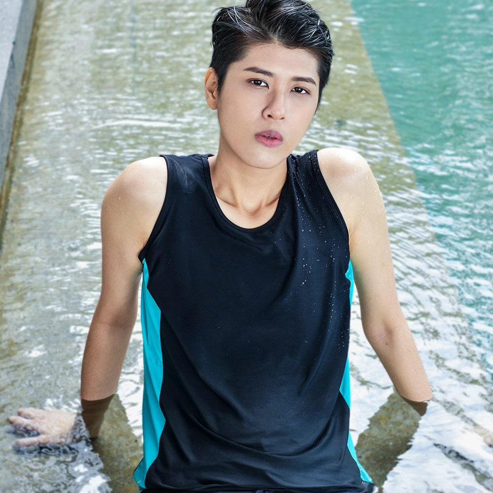 A non-binary androgynous tomboy, transgender man wearing a black color of a bandage TOMSCOUT Swimming Chest Binder to fight body dysphoria and swimming in the pool, TOMSCOUT SAPPHIRE SWIMMING BINDER.