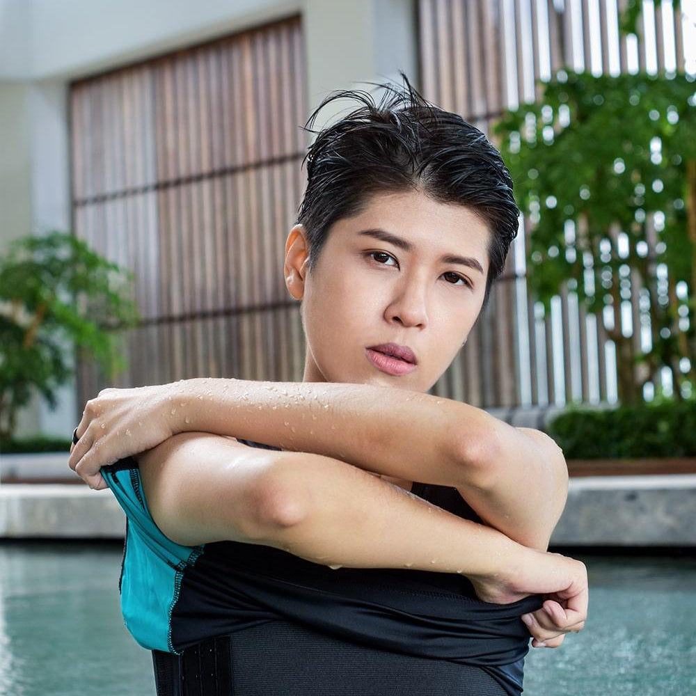 A non-binary androgynous tomboy, transgender man wearing a black color of a bandage TOMSCOUT Swimming Chest Binder to fight body dysphoria and swimming in the pool, TOMSCOUT SAPPHIRE SWIMMING BINDER.