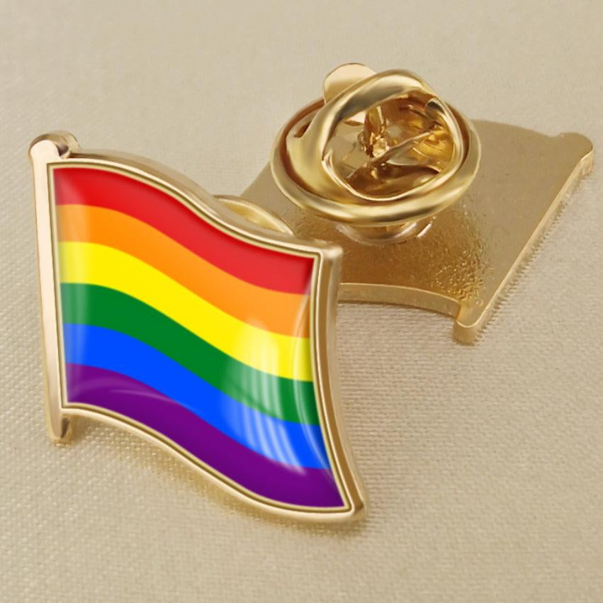 Product listing image of a TOMSCOUT LGBTQ+ Pride Metal Badge, pinned on a shirt, showcasing a symbol of pride and identity.