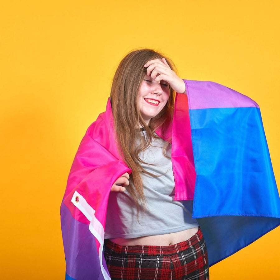 A bisexual young girl smiling and holding with a LGBTQ Bisexual Pride Flag, TOMSCOUT PRIDE  RAINBOW FLAG.