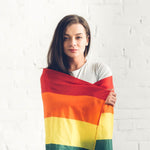 A young woman draped in an LGBTQ Rainbow Pride Flag, symbolizing protection and pride, from the TOMSCOUT LGBTQ+ Classic Pride Flag collection