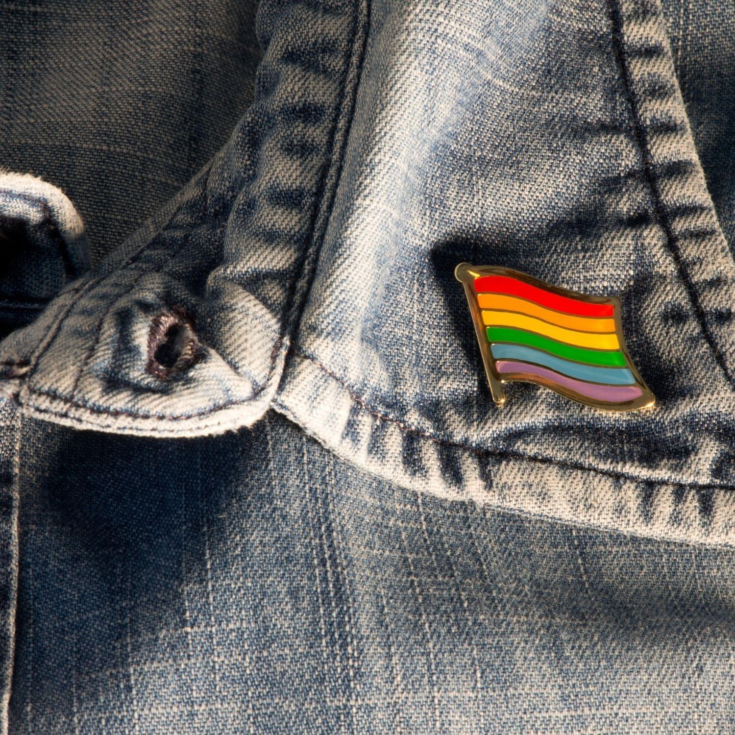 Product listing image of a TOMSCOUT LGBTQ+ Pride Metal Badge, pinned on a shirt, showcasing a symbol of pride and identity.
